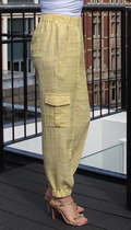 A pair of woven yellow joggers with a high waist and cargo pockets, modeled against an outdoor backdrop.