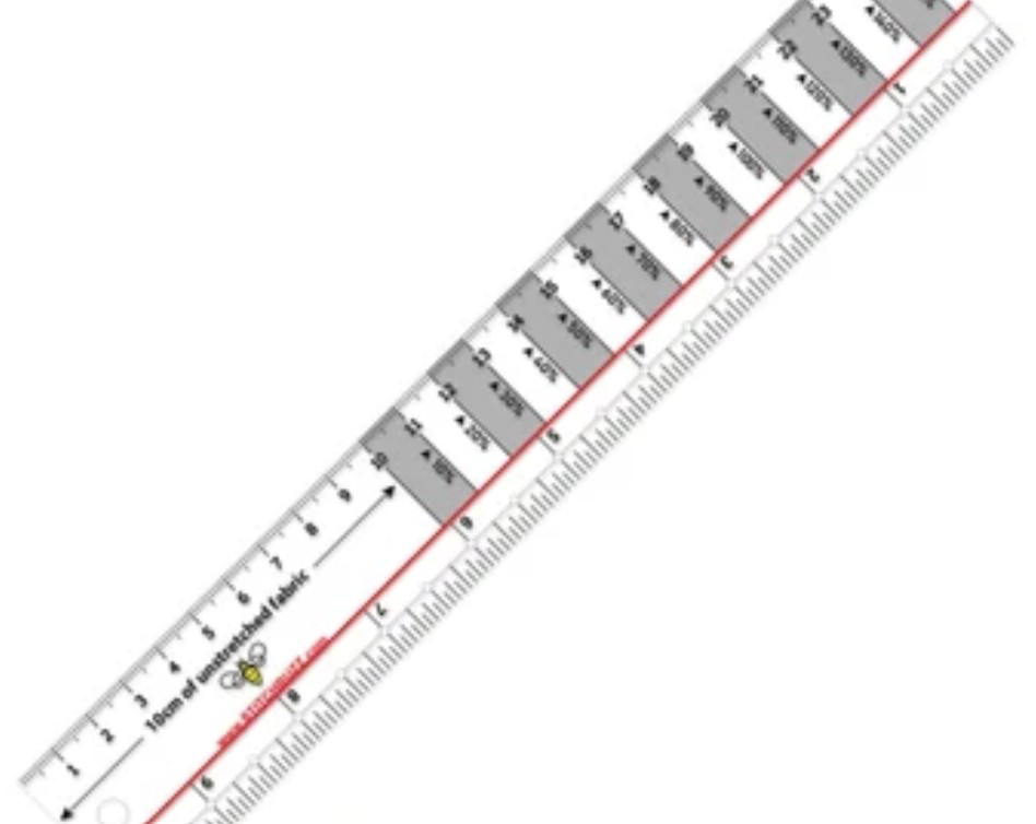 A 10-inch clear plastic ruler with gray stripes every other inch, used to measure the stretch and recovery of knit fabrics