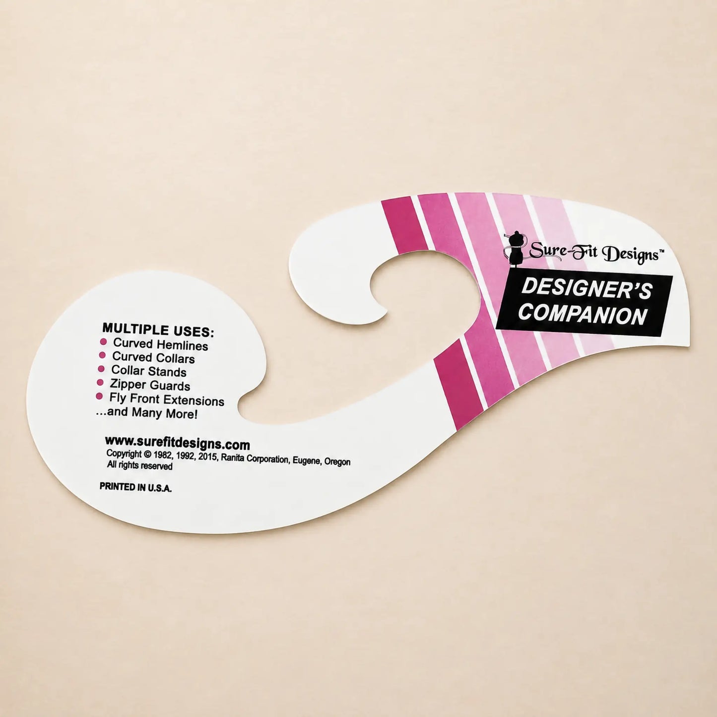 A Sure-Fit Designs Designer's Companion curved cardboard hanger insert on a light beige background, featuring pink and white diagonal stripes and black text.
