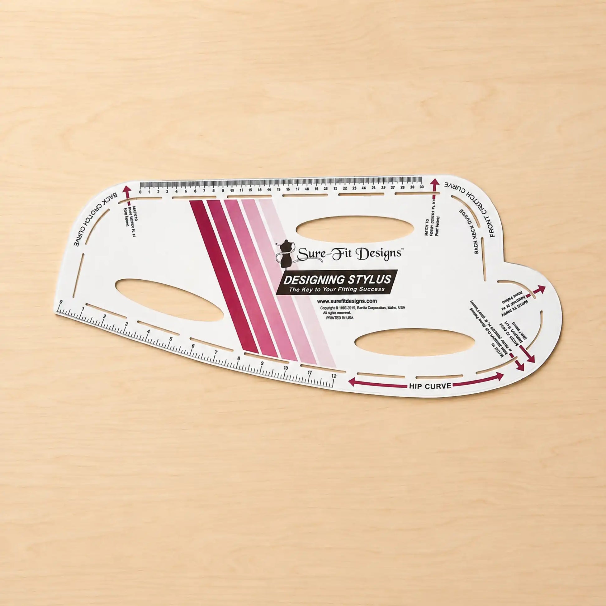 Sure Fit Designs Designing Stylus hip curve measuring tool on a light wood background.